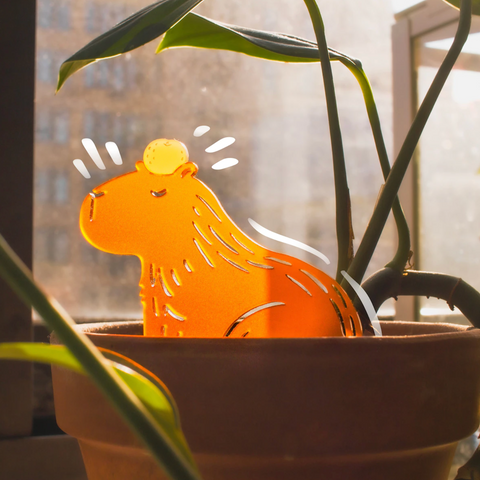 Orange cat-shaped lamp in a pot with a blurred indoor background