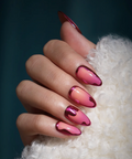 Hand with pink and red gradient nail polish on a white textured surface