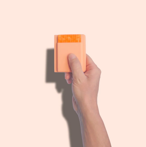 Hand holding a small rectangular object against a beige background