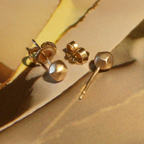 Gold earrings on a textured beige surface