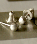 Pair of silver stud earrings on a textured surface