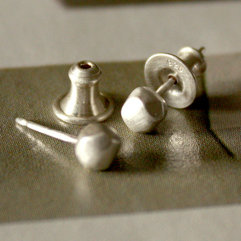 Pair of silver stud earrings on a textured surface