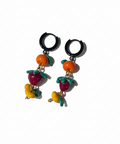 Pair of earrings with colorful fruit designs on a beige background