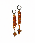 Pair of amber-colored chain earrings on a beige background