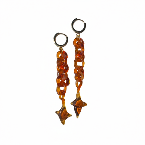 Pair of amber-colored chain earrings on a beige background