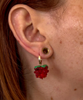 Close-up of an ear with a raspberry-shaped earring.