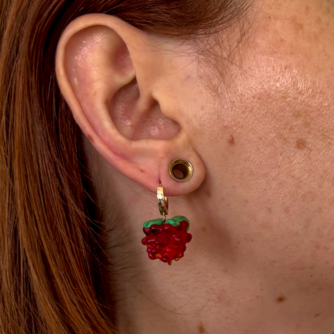 Close-up of an ear with a raspberry-shaped earring.