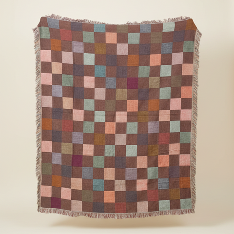 Multicolored checkered blanket draped over a pole outdoors.