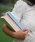 Person holding books with a blurred green background