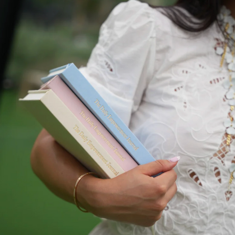 Person holding books with a blurred green background