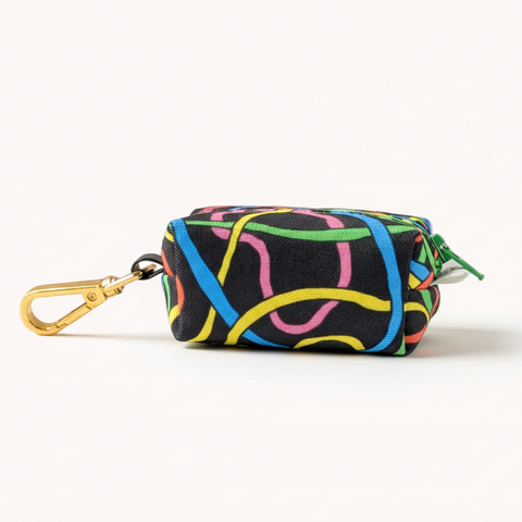 Multicolored patterned pouch with a gold clip on a light wooden surface