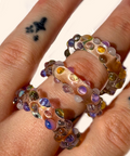 Close-up of a hand wearing a colorful beaded ring on a white background