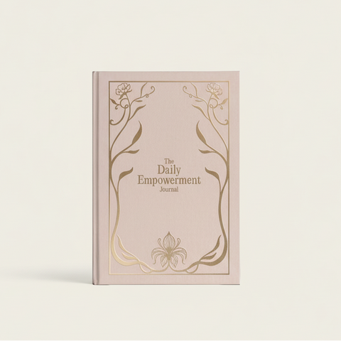 Pink journal titled 'The Daily Empowerment Journal' with decorative gold floral designs on a light gray background