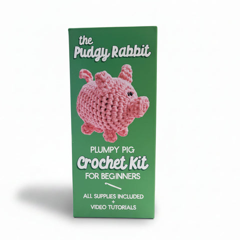 The Pudgy Rabbit Plumpy Pig Crochet Kit for Beginners in its green packaging box, featuring a pink crocheted pig illustration on the front.
