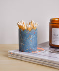 Blue speckled match holder with matches, on a light surface.