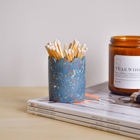 Blue speckled match holder with matches, on a light surface.