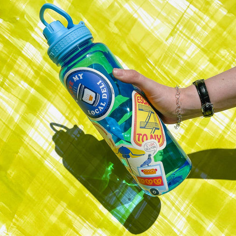 Person holding a colorful water bottle with a blue cap on a yellow background