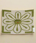 Knitted square with a smiling flower design on a white background