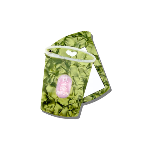 Compact mirror shaped like a matcha latte with a heart design on a white background