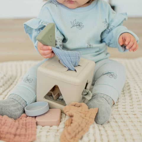 Child playing with wooden blocks on a soft surface