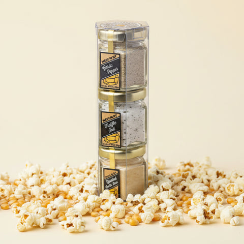 Stack of gold-colored cubes containing various spices with labels in a clear plastic packaging on a wooden surface.