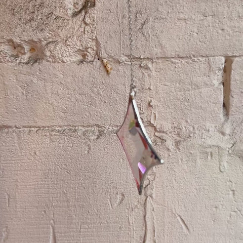 a video of a magenta star shaped sun catcher spinning around.